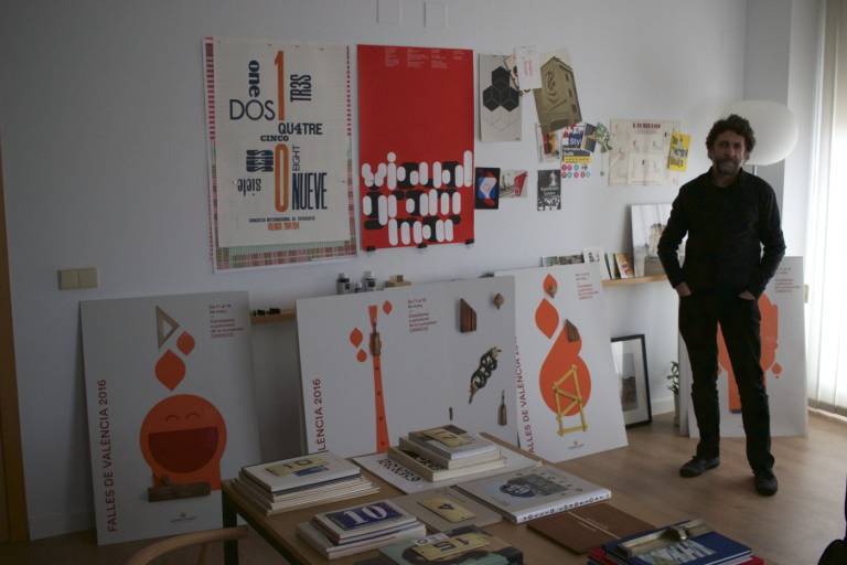 El diseñador Ibán Ramón en su estudio junto a los cuatro carteles de Fallas 2016