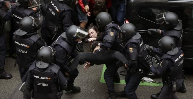 Un grupo de antidisturbios saca a la fuerza a una mujer. Foto: EFE