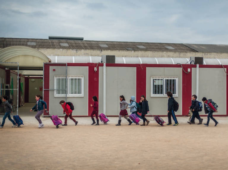 Un grupo de alumnos sale de un colegio con barracones. Foto: BIEL ALIÑO