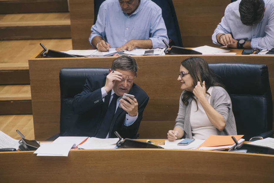 El presidente de la Generalitat mria su móvil mientras dialoga con Oltra. Foto: KIKE TABERNER