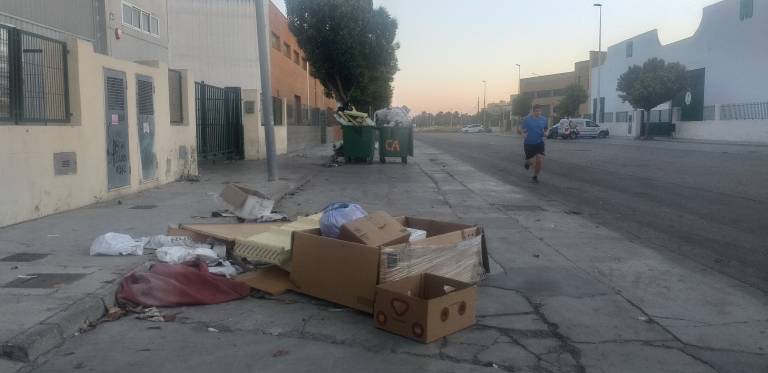 Un corredor pasa junto a la basura esparcida en la calle de un polígono de un pueblo de Valencia.