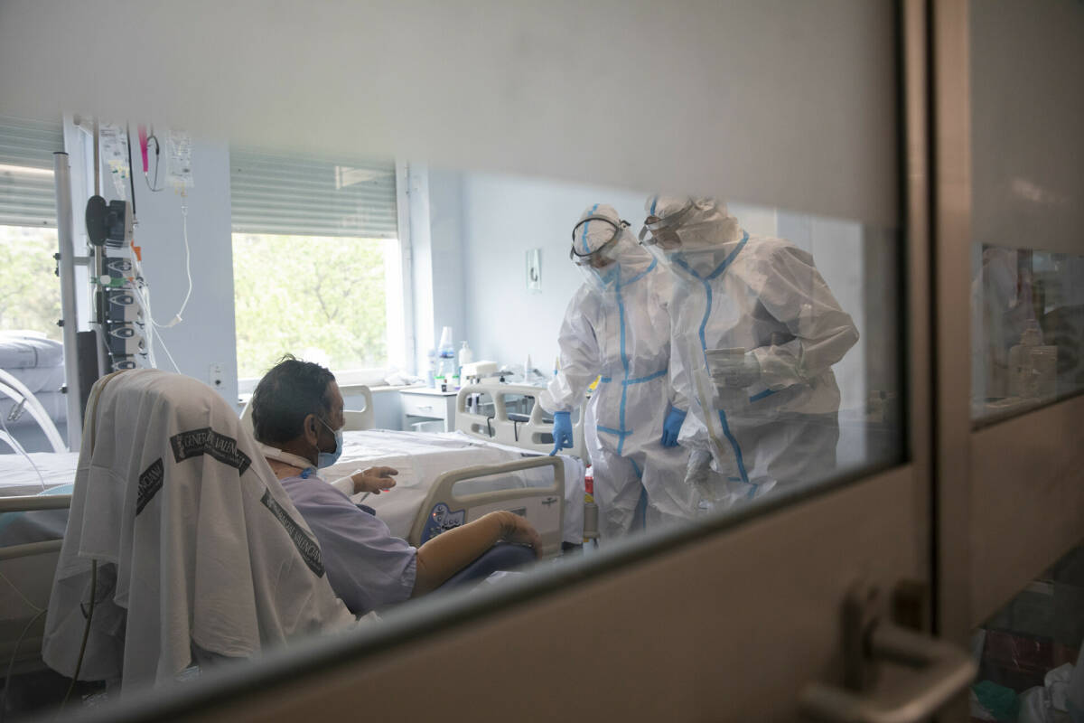 Sanitarios con un paciente en la UCI del Hospital Clínico de València. Foto: EVA MÁÑEZ
