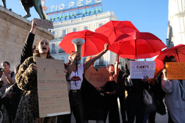 Varias trabajadoras sexuales con carteles y paraguas rojos, durante una protesta contra la legislación en la prostitución, en la Puerta del Sol, a 22 de octubre de 2021, en Madrid (España). Foto: Isabel Infantes / Europa Press